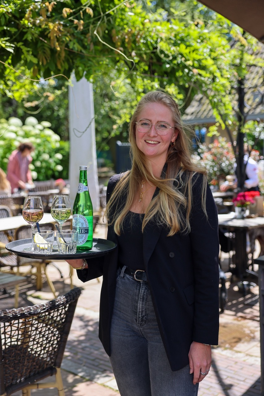 bedieningsmedewerker alana lacht en staat op het terras